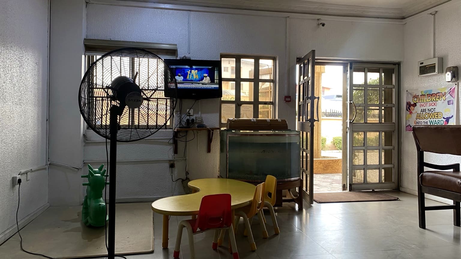 Waiting area at Banby Specialist Hospital in Ibadan, with a wall-mounted television, a standing fan and a children's table and chairs